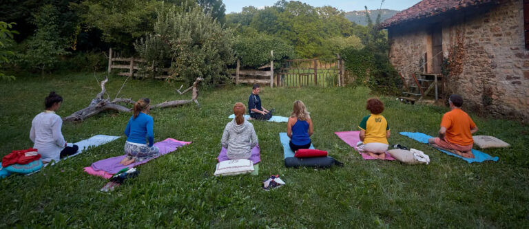 Grupo practicando yoga en agosto en el jardin del Centro de Retiros de Yoga y Meditación Pirineos de Arrieta, Navarra