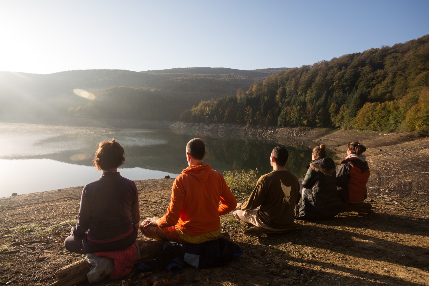 a group of people sitting and standing in front of a mountain